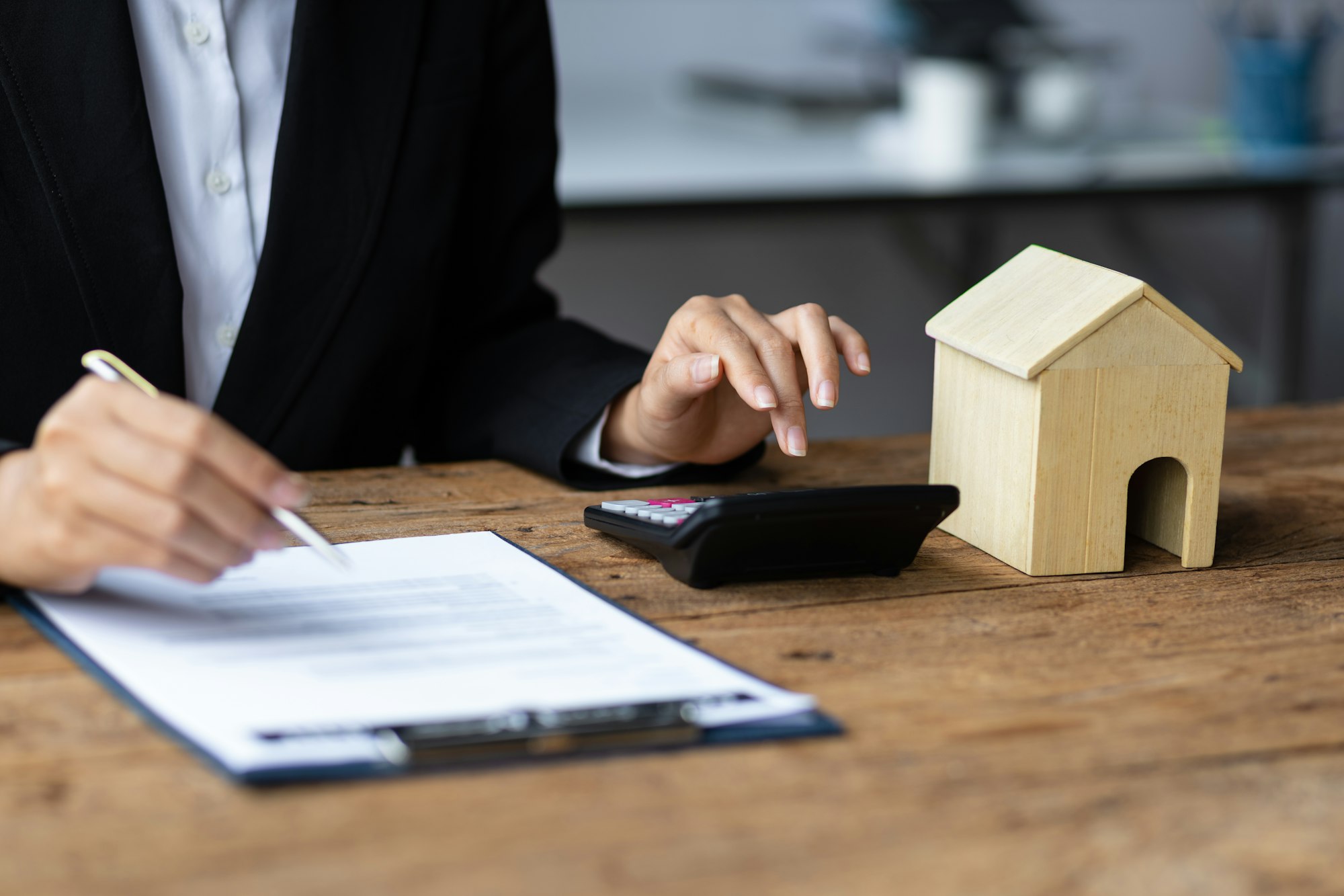 Businesswoman, real estate agent reading contract documents and calculating real estate budget.