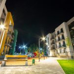 Yard between residential apartment buildings with empty wooden bench and modern flat housing. Real